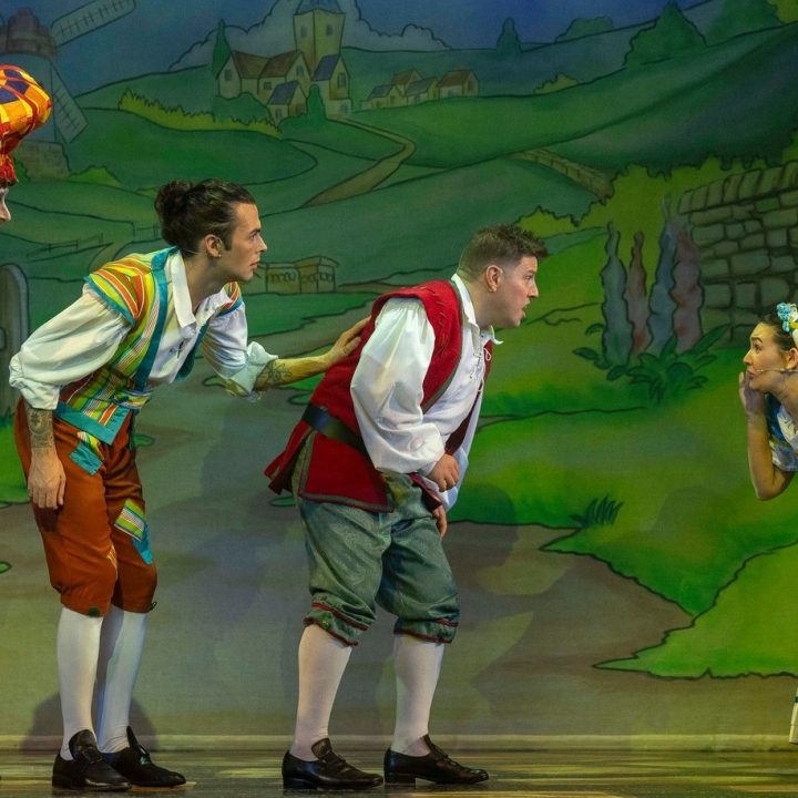 Four actors perform on Grove Theatre stage in a colourful theatrical scene.