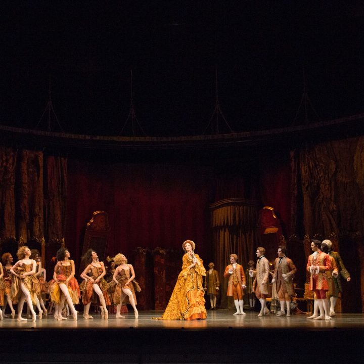 A stage performance featuring a group of ballet dancers in elegant costumes.
