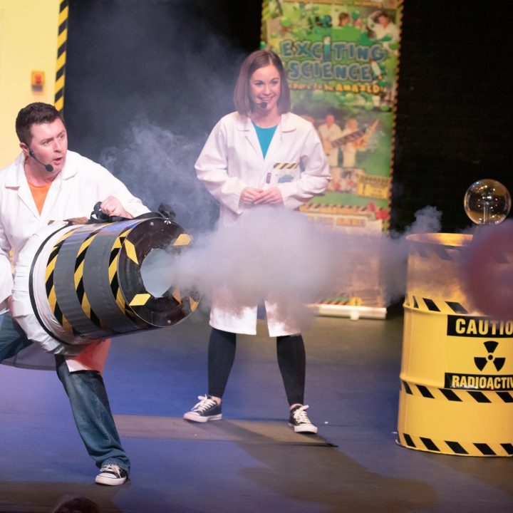 Two people in white lab coats perform a science experiment.