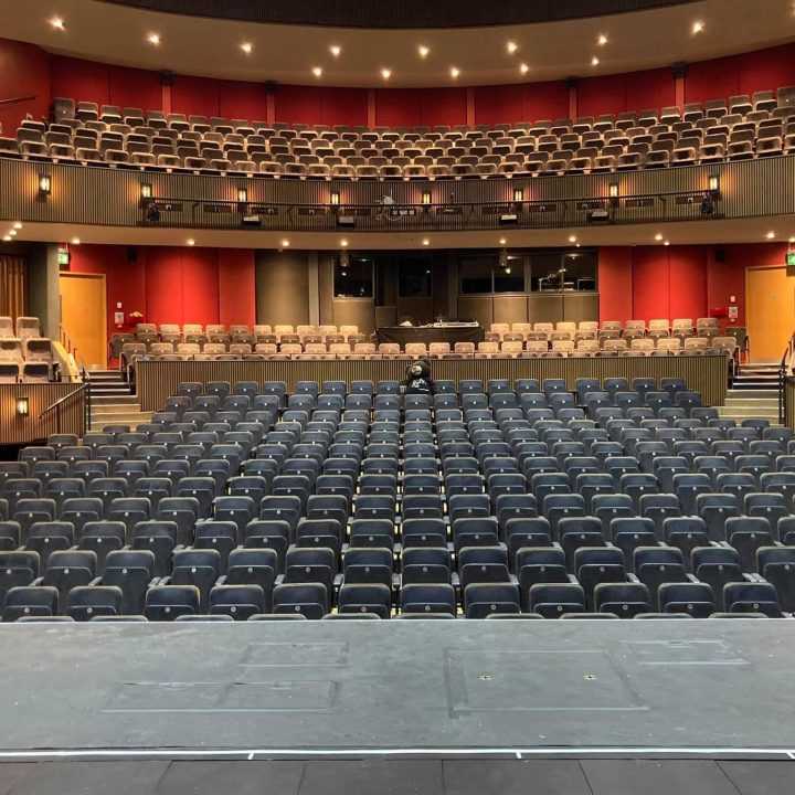 A large, empty Grove Theatre with rows of black seats.