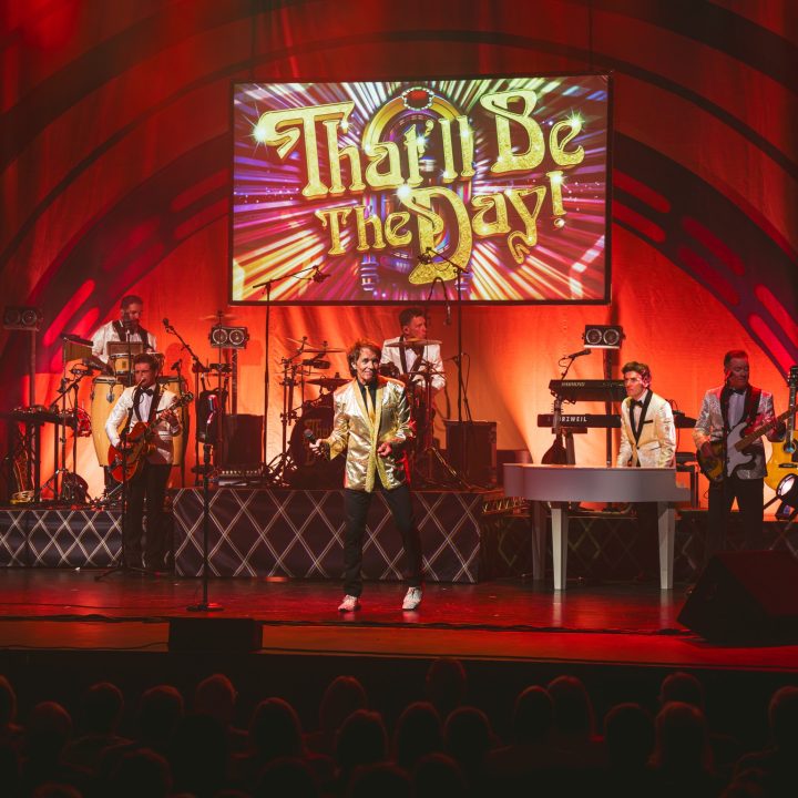 A live band performs on stage with vibrant red lighting.
