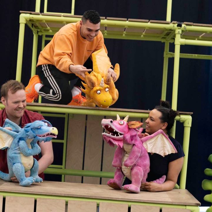 Four people are interacting with colourful dragon puppets.