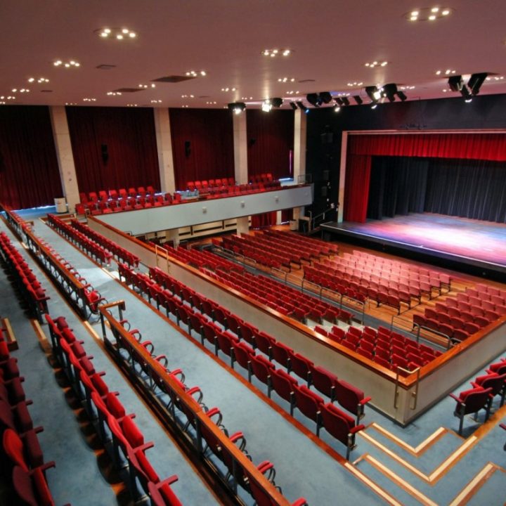 A view of a large, empty Alban Arena theatre with red seats.