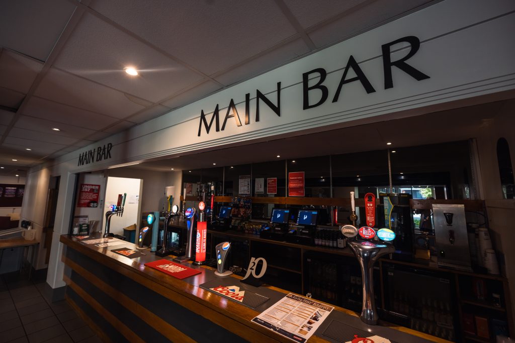 A bar interior with taps, glasses, and a "Main Bar" sign offers pre-ordering options.