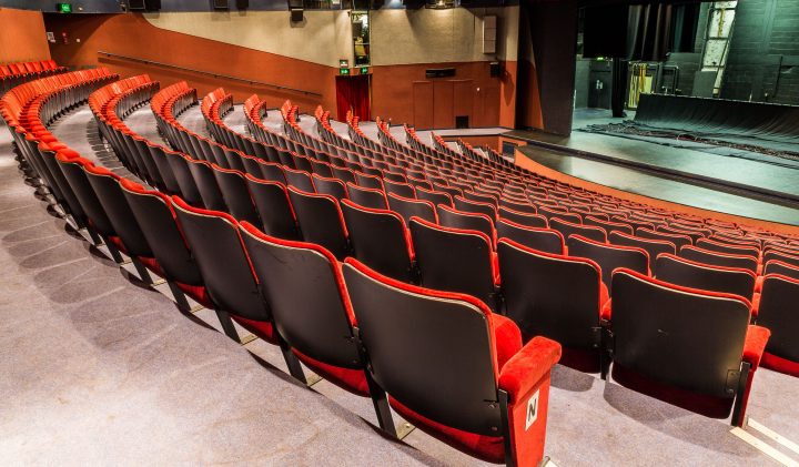 Empty theatre with red and black seats; perfect venue hire.