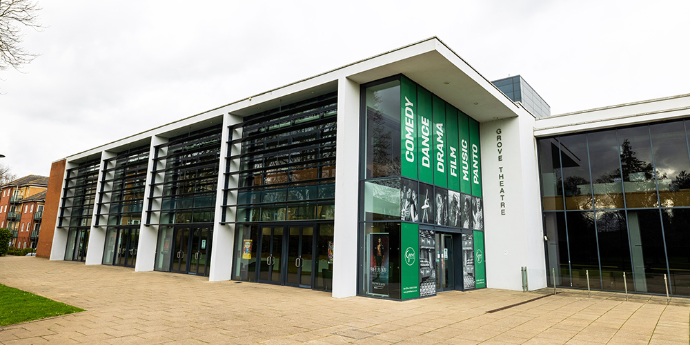 Modern theatre, Grove Theatre, with green banners and ample parking.