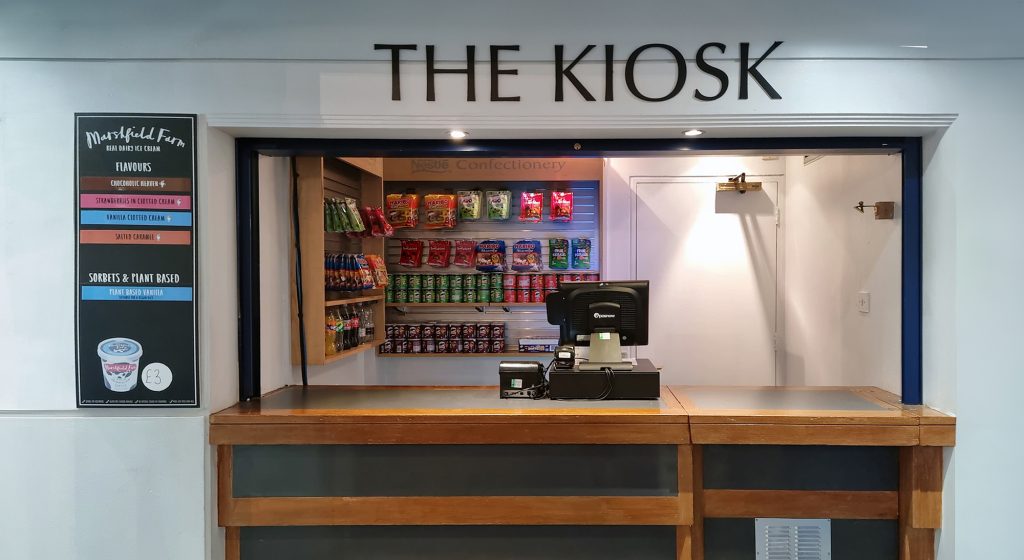 Small kiosk with snacks and ice cream on shelves behind the counter.
